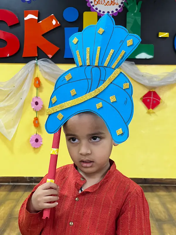A boy with a paper turban prop at the Baisakhi celebration