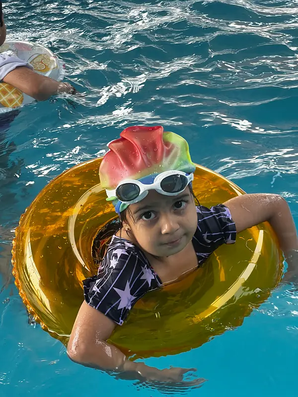 A girl floating in a swim ring at the summer camp pool