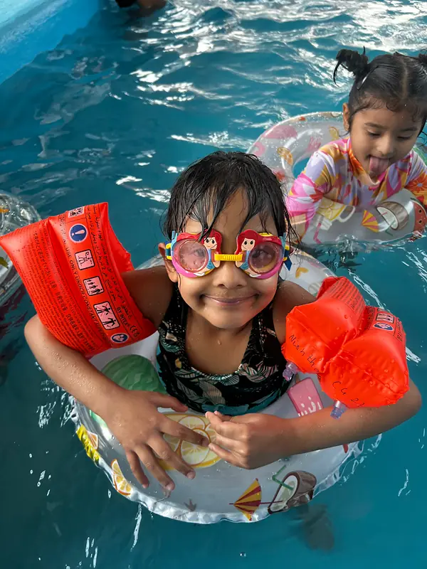 A smiling swimmer with goggles and arm bands