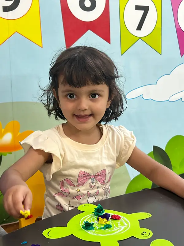 A girl smiling while making a paper turtle craft