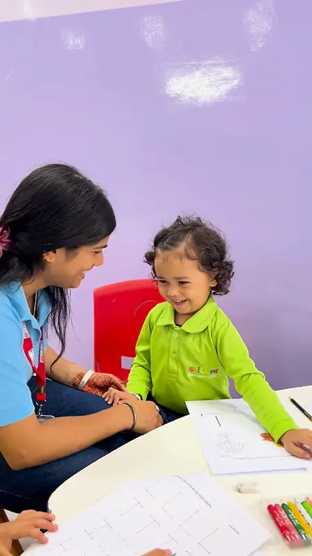 A teacher and a smiling girl work through a worksheet together