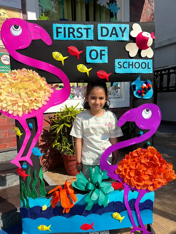 A student smiling beside the First Day of School board