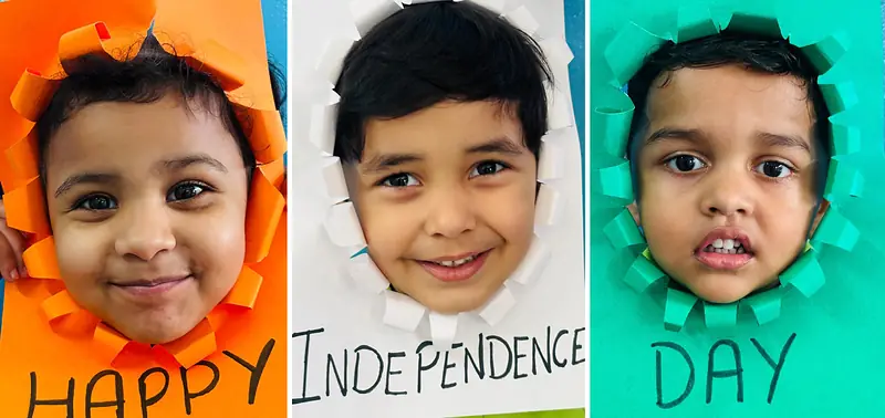 Three students spell out Happy Independence Day through paper frames