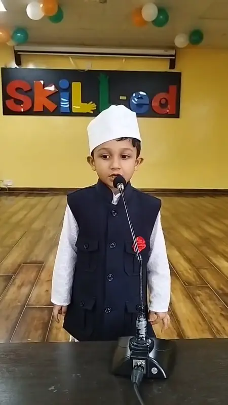 A boy dressed as Jawaharlal Nehru speaks at the podium