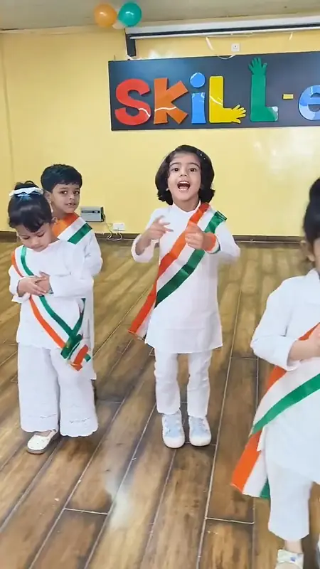 Children in white kurtas and tricolour sashes during their dance