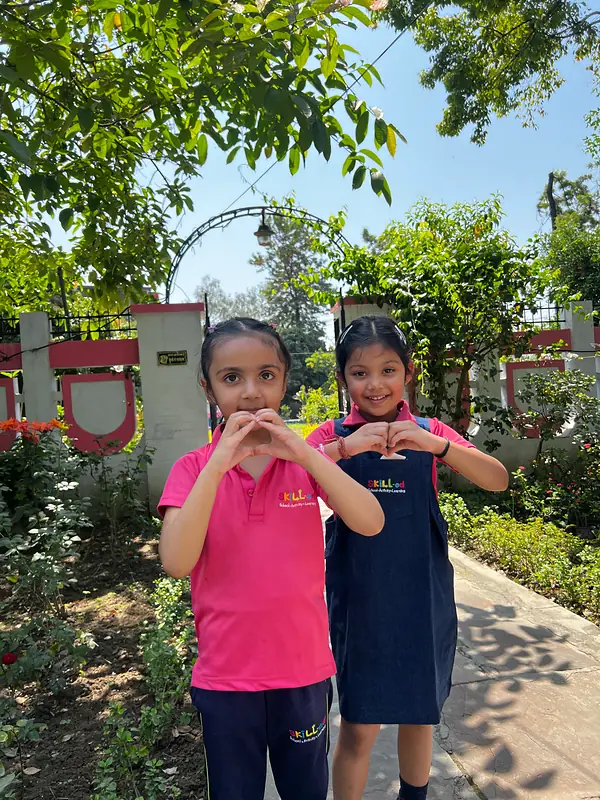 Two girls make heart shapes with their hands on the plant nursery visit
