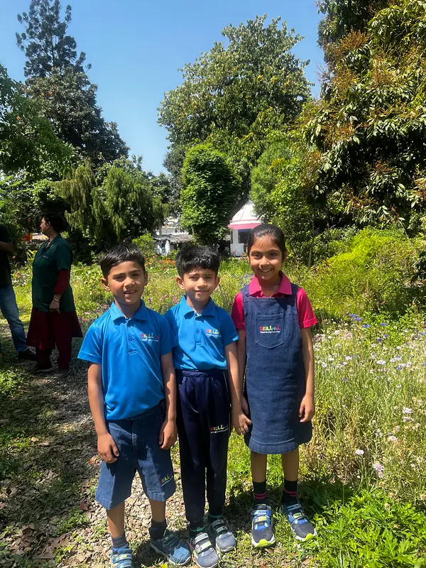Three classmates on a garden path at the plant nursery